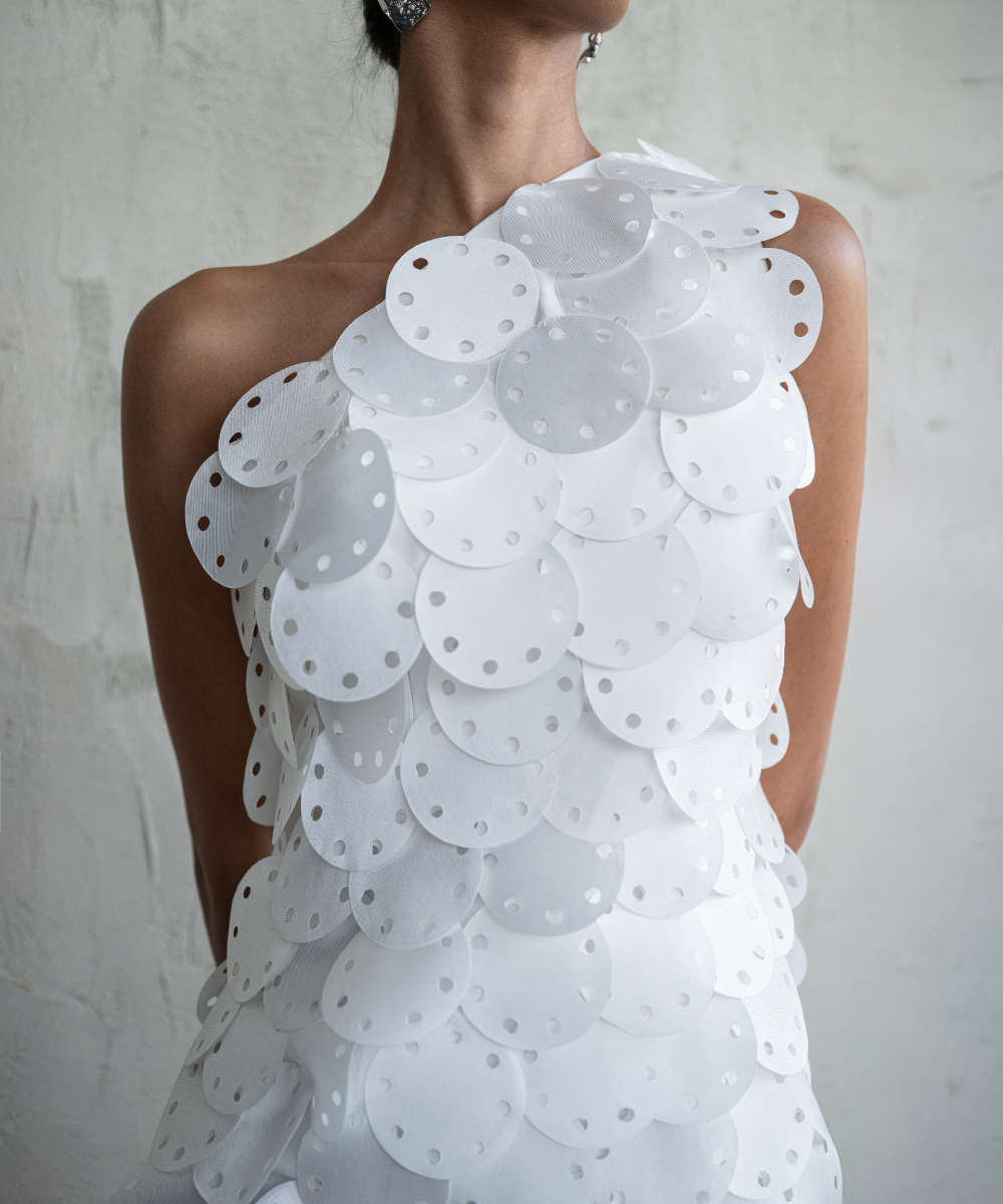 Woman wearing a white lace dress against a plain background